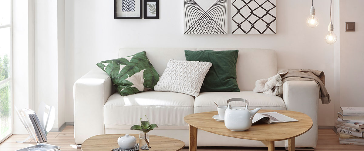 Skandinavisches Wohnzimmer: Sofa, mit Couchtisch und Bilder mit grafischem Muster. 