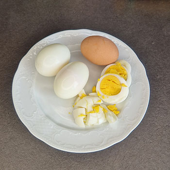 Gekochte und zum Teil gepellte und geschnittene Eier auf einem Teller.