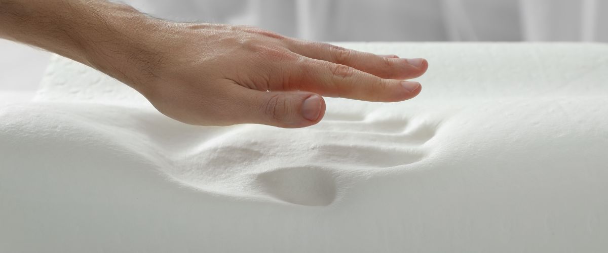 Eine Hand über einer Fläche aus Memory Foam Schaum, der einen passenden Handabdruck aufweist.