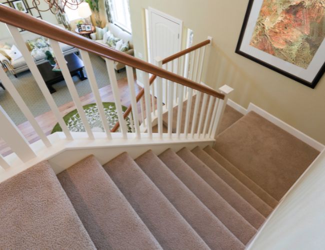 Eine von oben fotografierte Treppe mit braunem Teppich auf den Stufen.