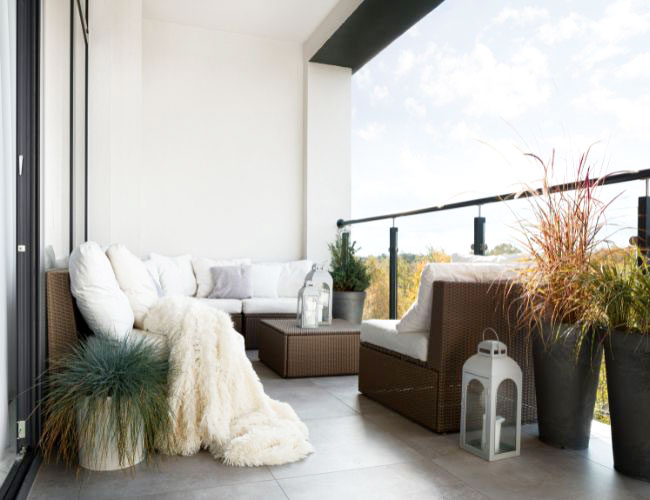 Ein gemütlich eingerichteter Balkon mit Balkonmöbeln aus Polyrattan, Pflanzen und Dekoration.